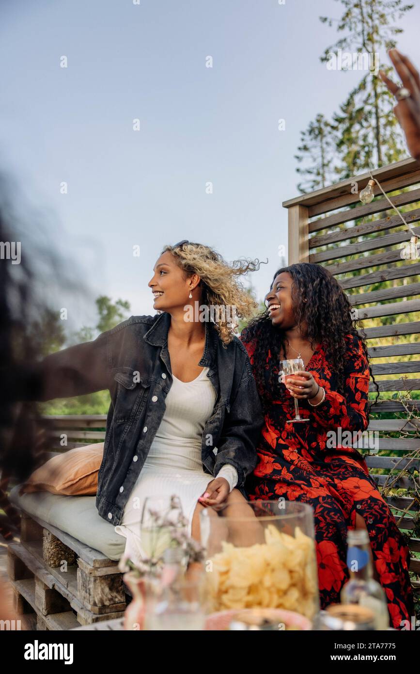 Smiling young female friends looking away during dinner party Stock Photo