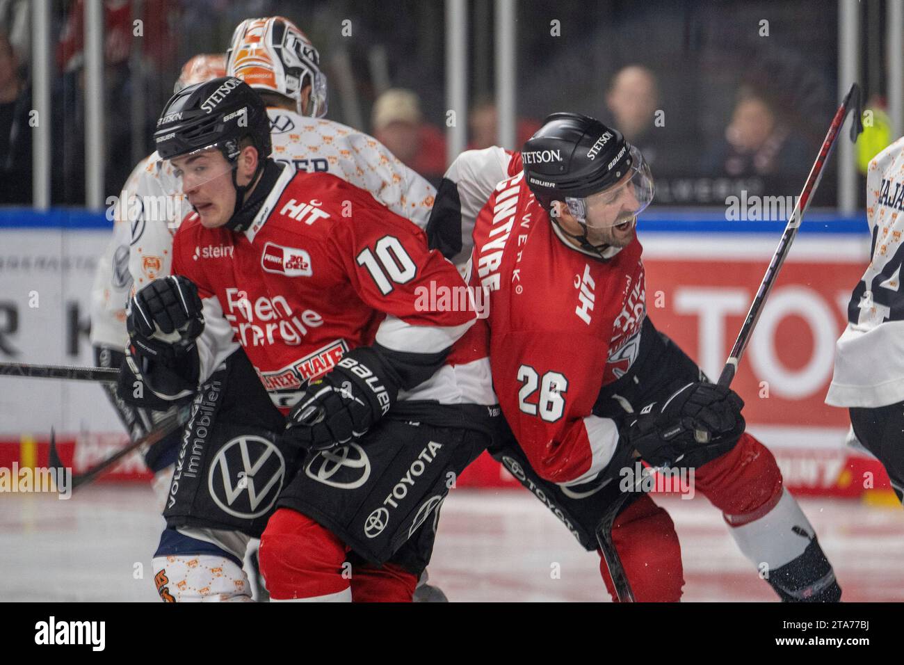 28.11.2023, Lanxess-Arena, Koeln, GER, DEL, Koelner Haie vs Grizzlys Wolfsburg, 22.Spieltag, Saison 2023/24, Im Bild: David McIntyre (Kölner Haie, #26) wird von Justin Feser (Grizzlys Wolfsburg, #71) hart attackiert im Zweikampf, Duell, Dynamik, Aktion, Action, Spielszene; Gestik, Mimik, Emotionen; Schmerz Justin Schuetz (Kölner Haie, #10) versucht zu klären Foto © nordphoto GmbH/Denkinger Stock Photo