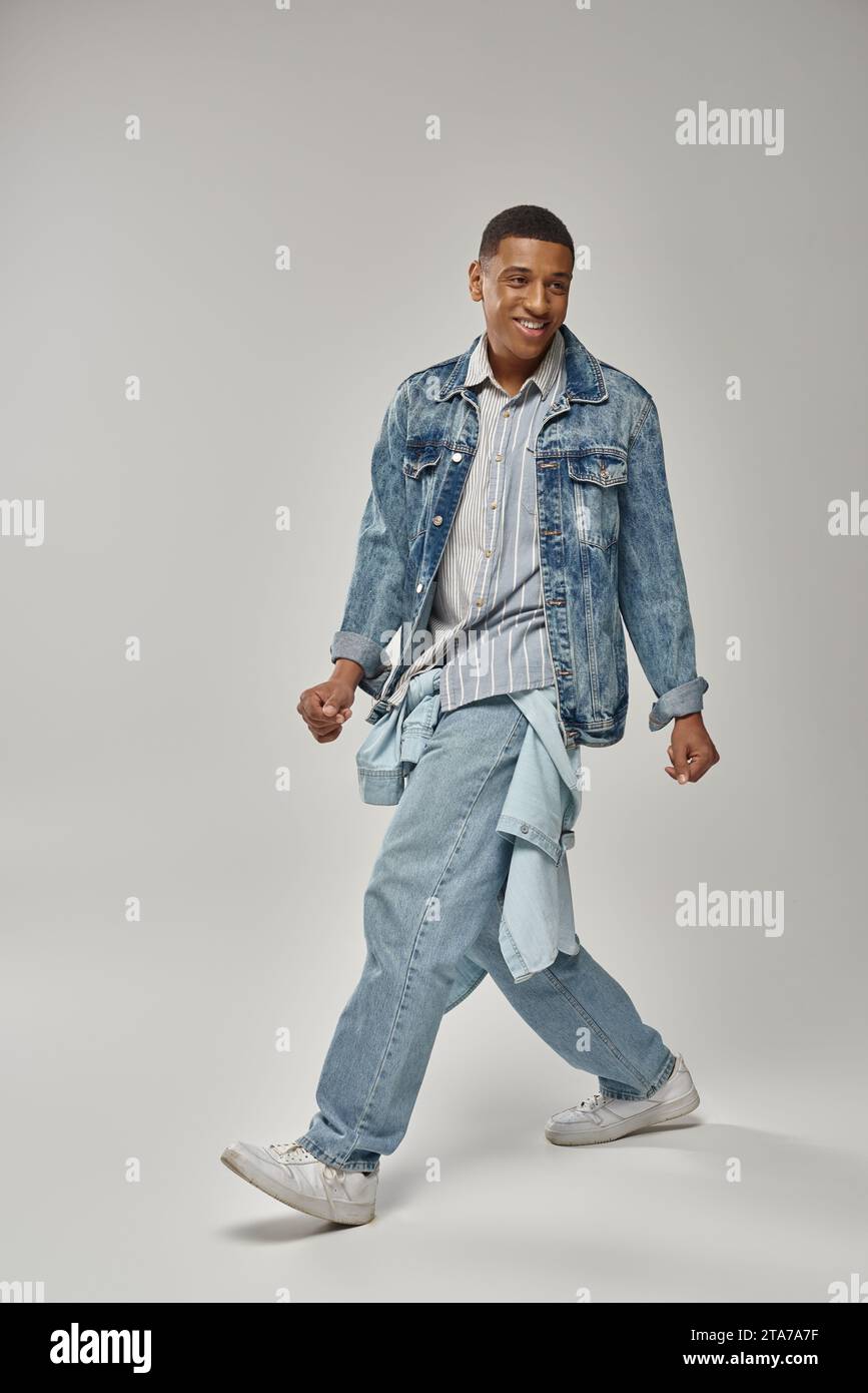 young trendy african american man in stylish denim outfit posing on white backdrop, fashion Stock Photo
