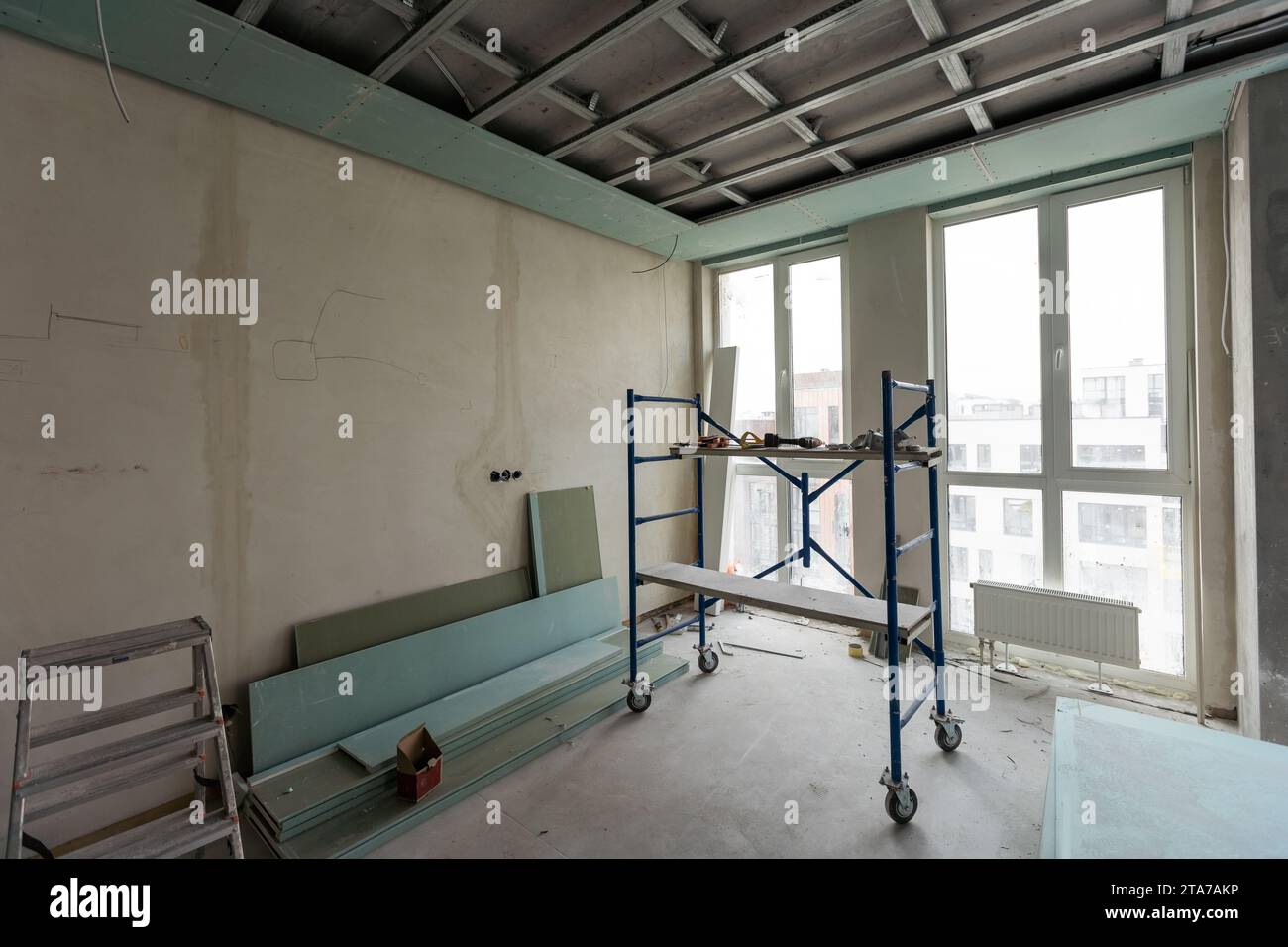 Installation of drywall. Workers are using screws and a screwdriver to attach plasterboard to the ceiling Stock Photo