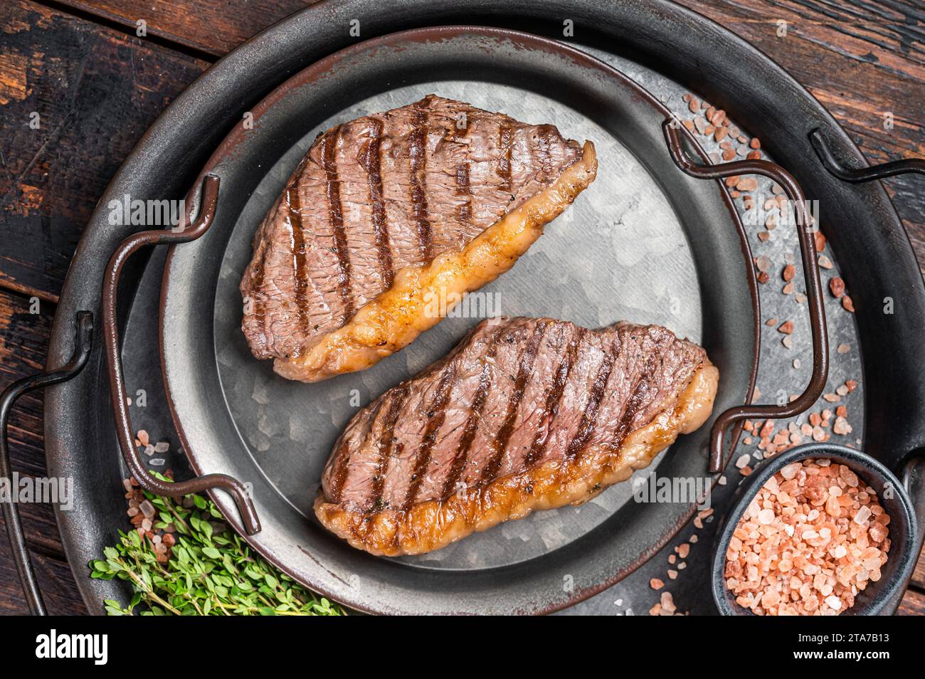 BBQ Grilled top sirloin steak, cup rump beef meat steak in a steel tray. Wooden background. Top view. Stock Photo