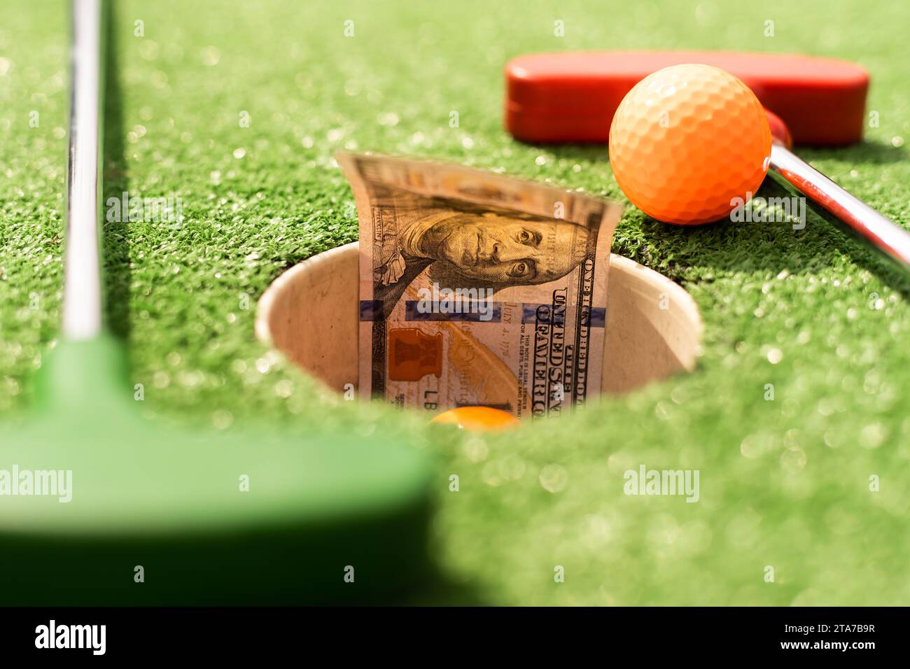 Mini Golf club, ball and money on the artificial grass Stock Photo