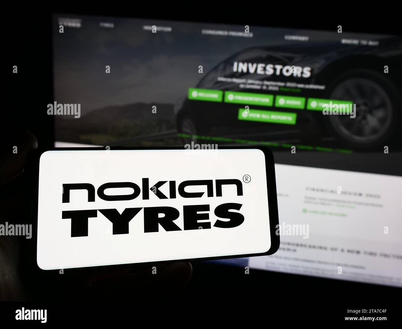 Person holding smartphone with logo of Finnish tyres manufacturing company Nokian Tyres in front of website. Focus on phone display. Stock Photo