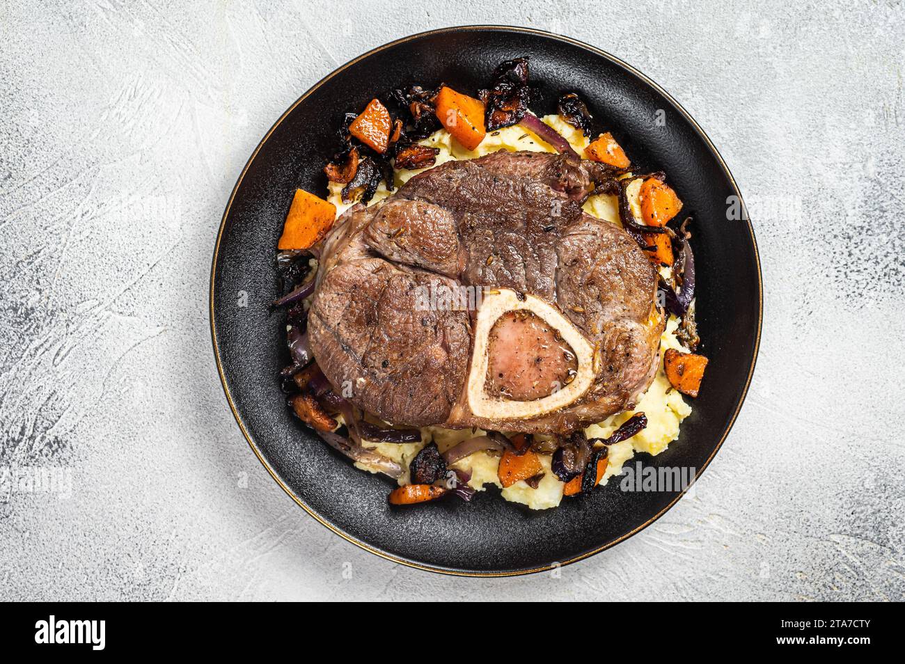 Osso buco cross cut veal shank with mashed potato on a plate. White background. Top view. Copy space. Stock Photo