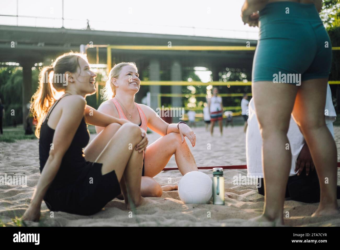 Smiling female friends talking to each other during volleyball match Stock Photo