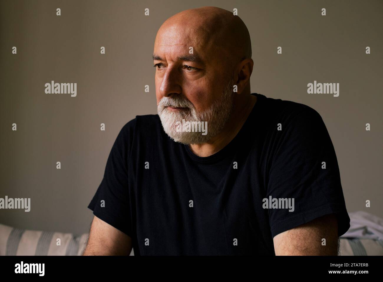 Depressed mature man with shaved head at home Stock Photo