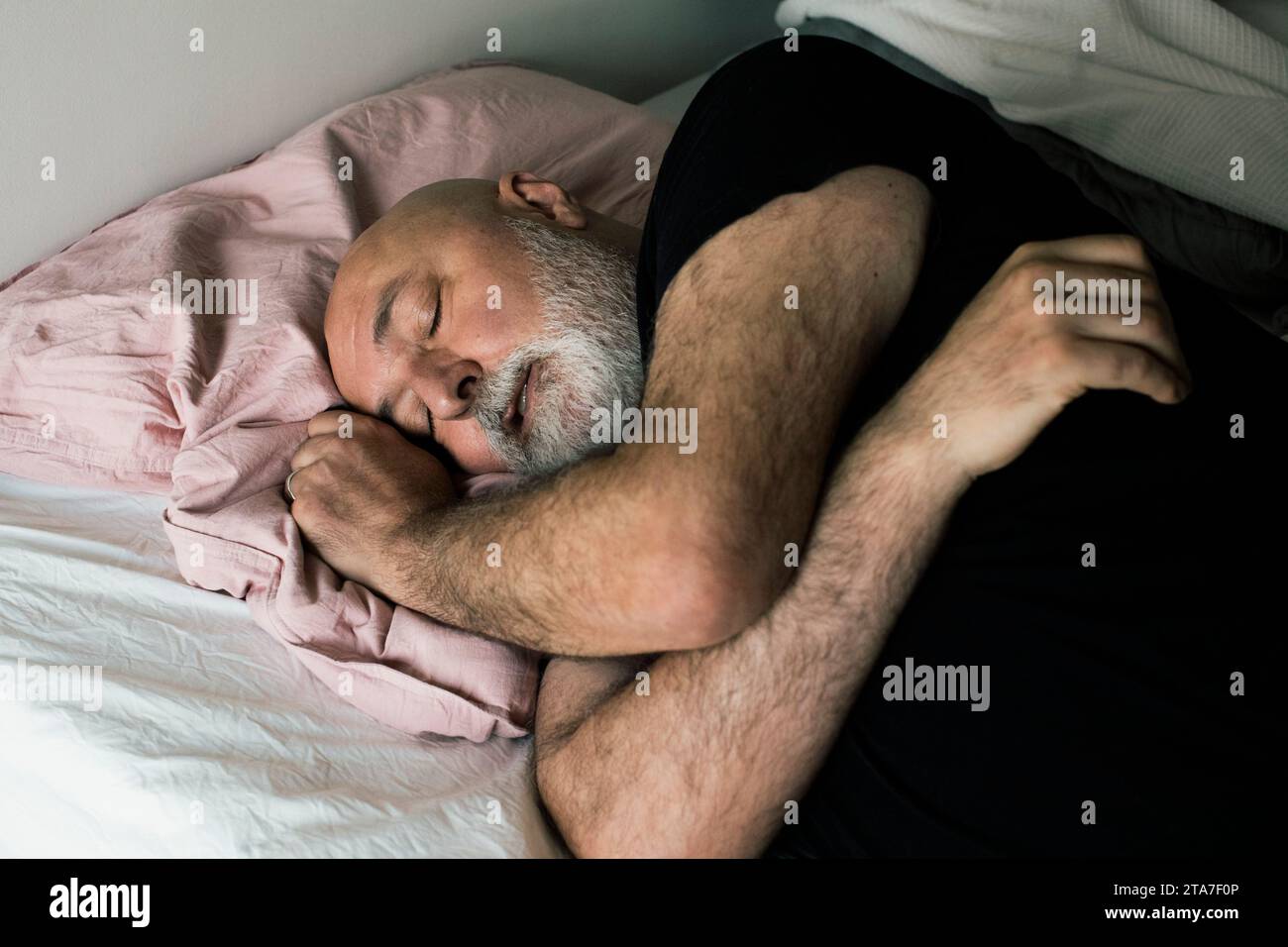 Exhausted mature man lying down on bed at home Stock Photo