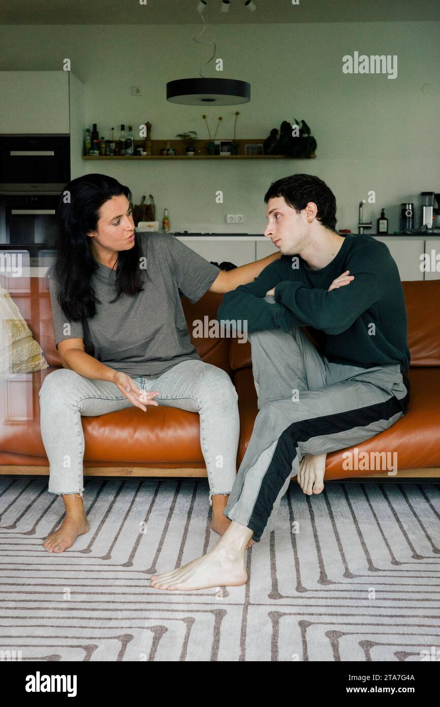 Mother consoling son while sitting on sofa at home Stock Photo