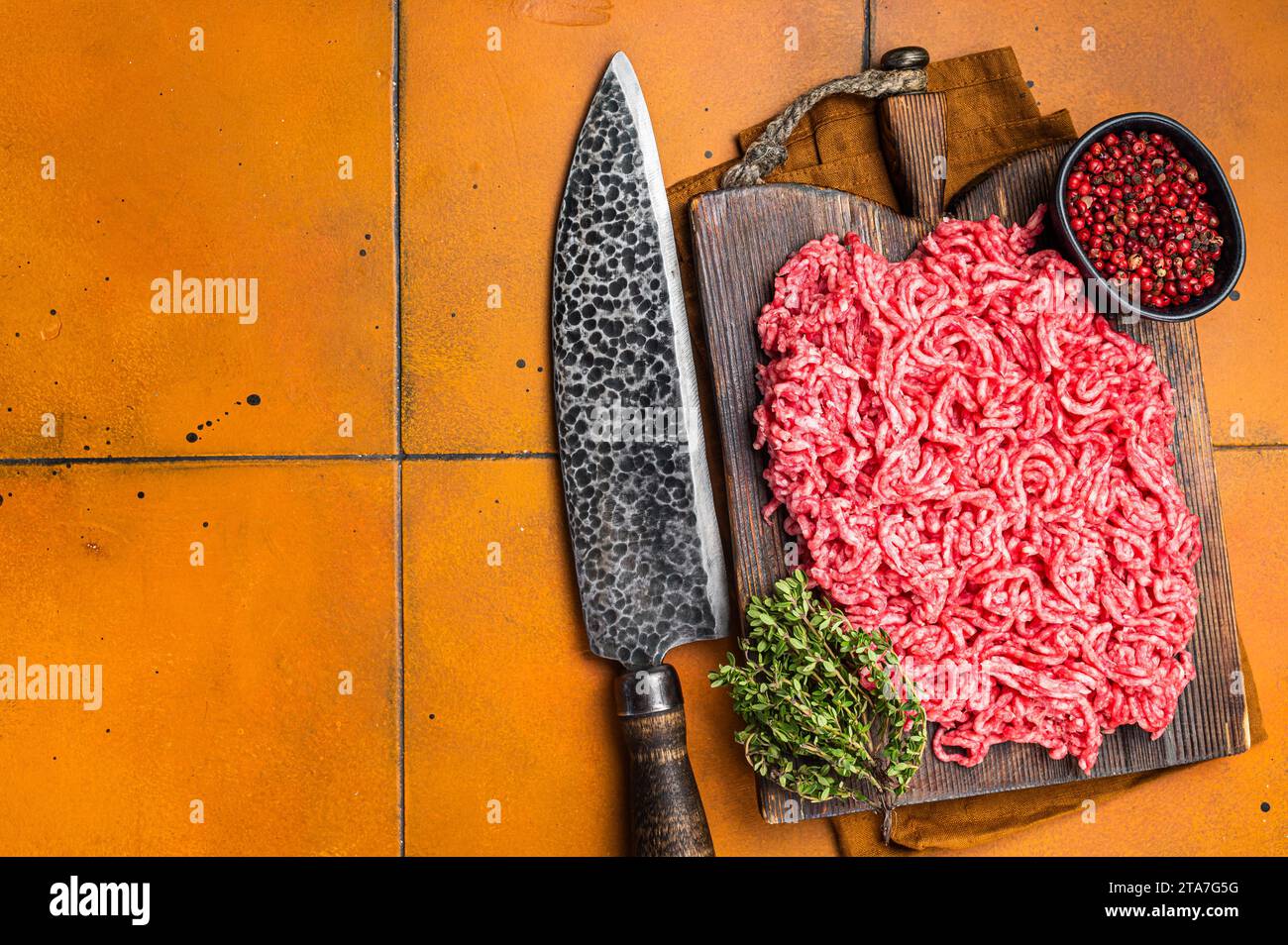 Fresh Raw Mince, Ground beef and pork meat on a butcher board. Orange background. Top view. Copy space. Stock Photo