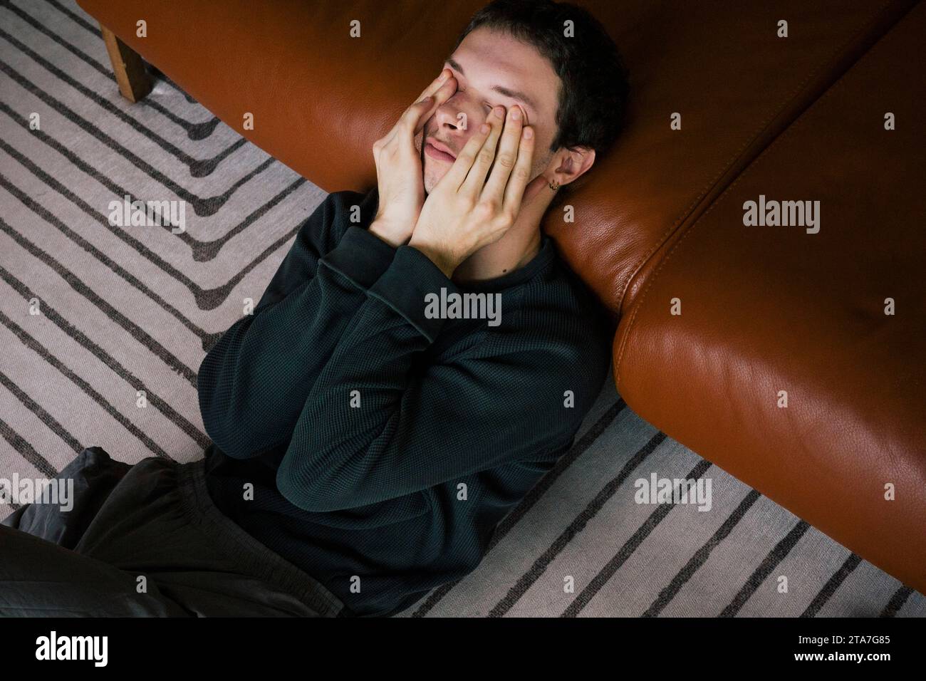 High angle view of man rubbing eyes while reclining on sofa at home Stock Photo