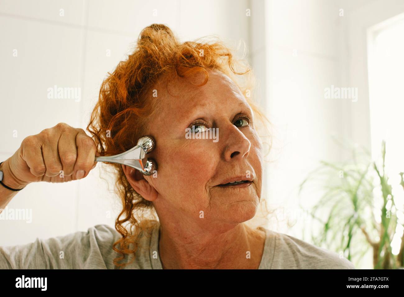 Elderly woman with redhead massaging face at home Stock Photo