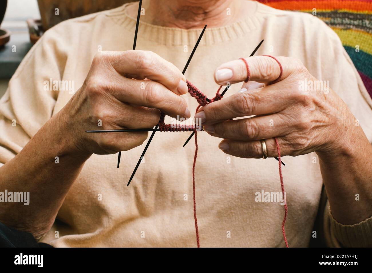Midsection of elderly woman knitting while sitting at home Stock Photo