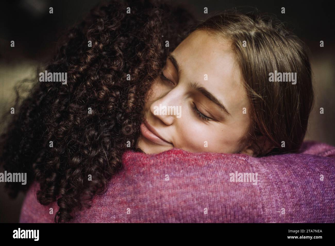 Girl embracing female friend with eyes closed Stock Photo
