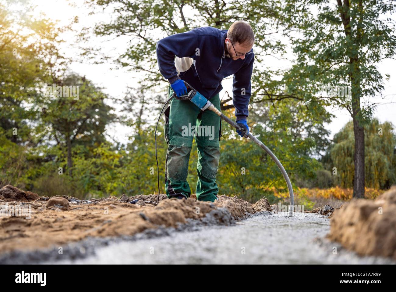 Construction worker using a concrete vibrator to compact the foundation