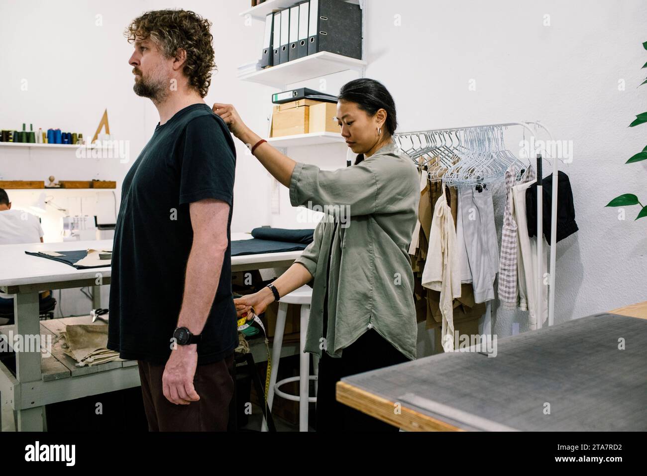 Female tailor taking measures of male customer at workshop Stock Photo