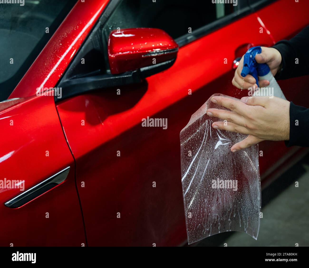 A technician sprays water before applying protective vinyl film to a