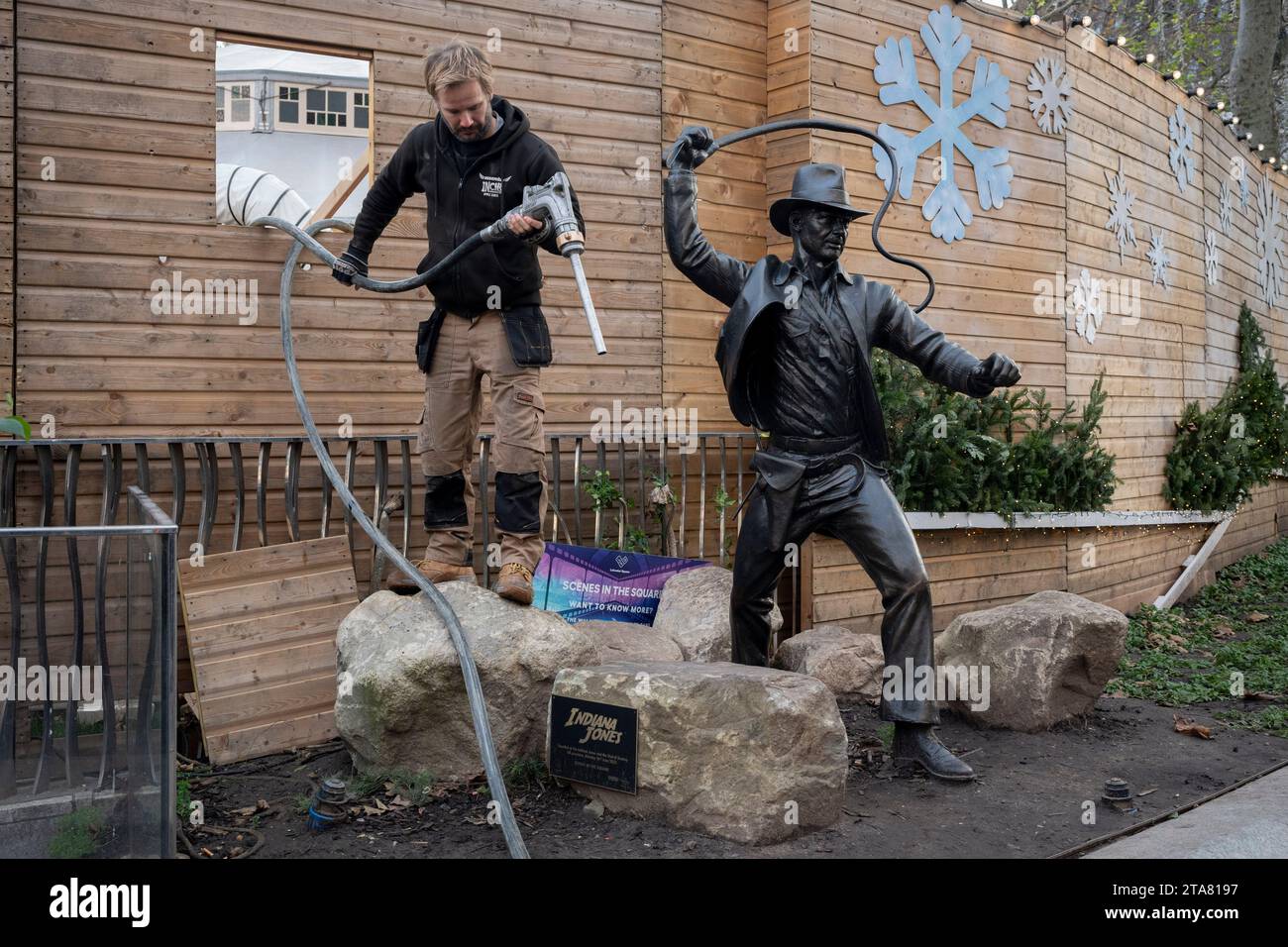 A contractor finishes with pumping fuel through a hoarding aperture alongsiode the Indiana Jones action hero character in Leicester Square, on 29th November 2023, in London, England. Stock Photo