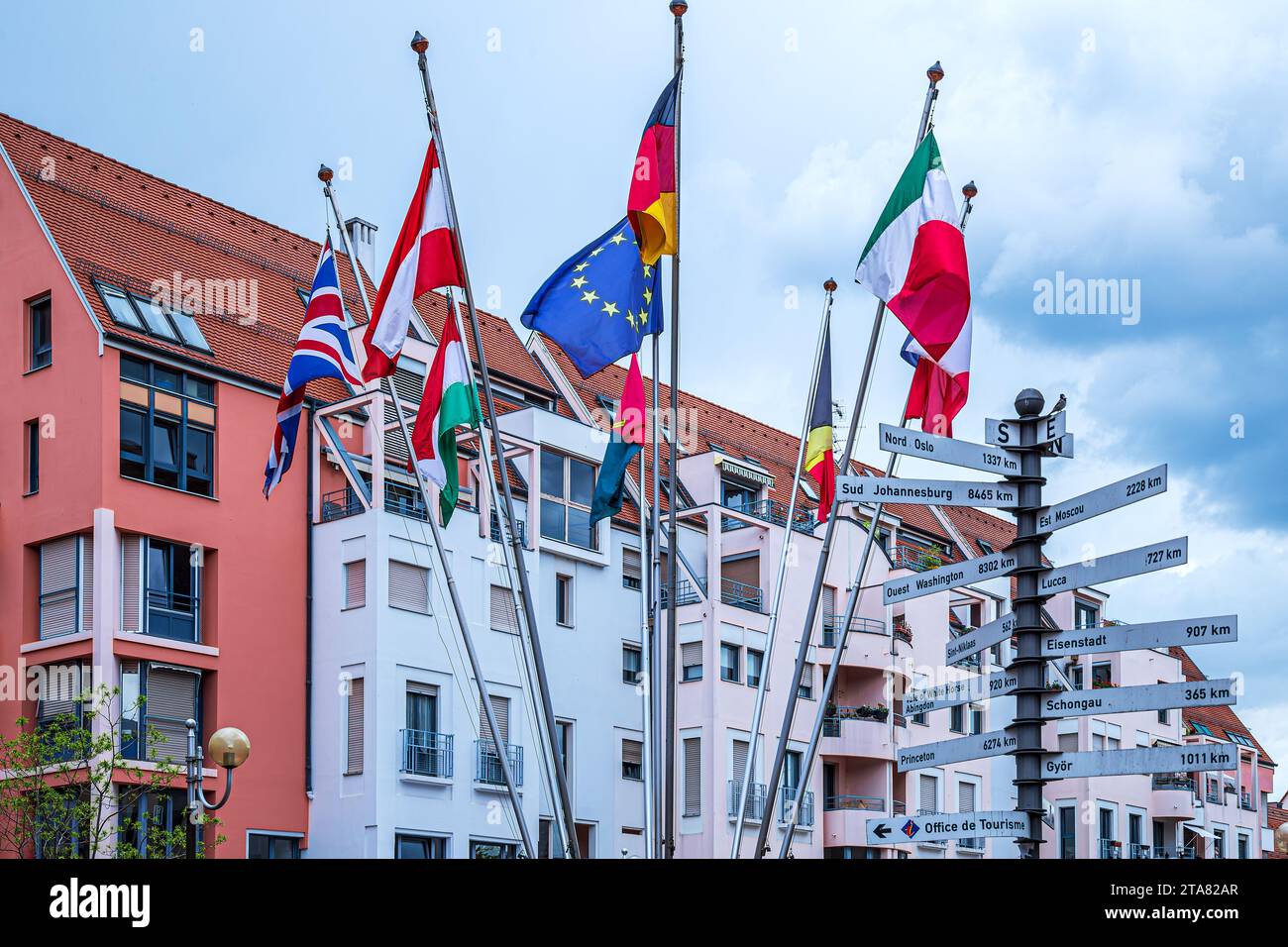 COLMAR, ALSACE, FRANCE - MAY 5, 2023: Flags of several EU countries and a pole with tablets on which the main cities of the globe are inscribed, with Stock Photo