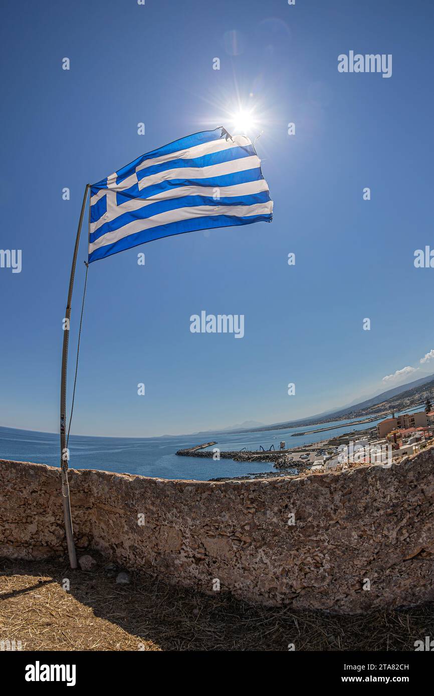 Rethymno,Crete island,Greece-June 18,2021:The national Greek flag fluttering from the height of hill called Paleokastro and of the Venetian Fortezza C Stock Photo