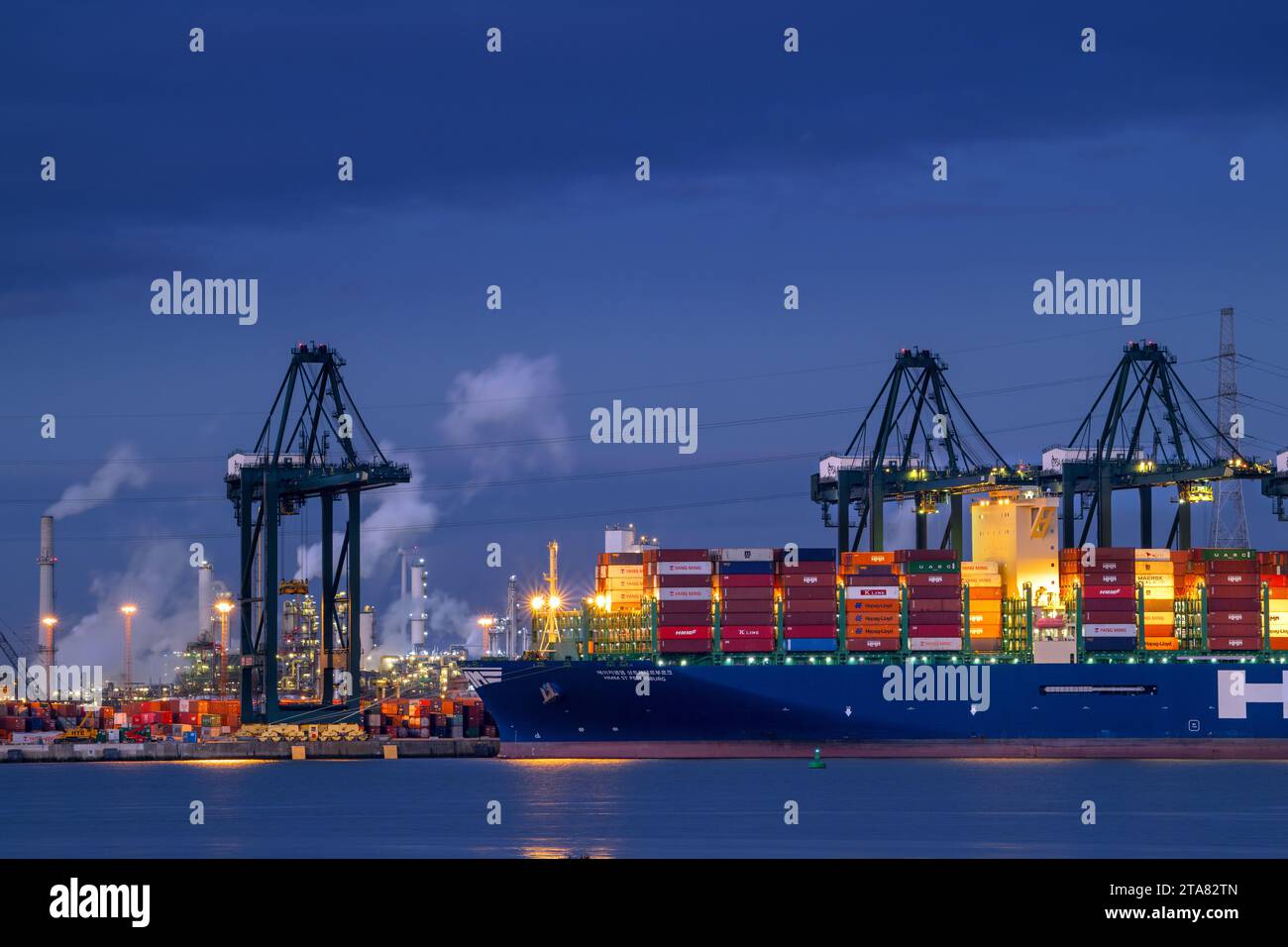Container ship with stacked containers and gantry cranes at container terminal in the Antwerp port at night along the Western Scheldt, Flanders, Belgi Stock Photo