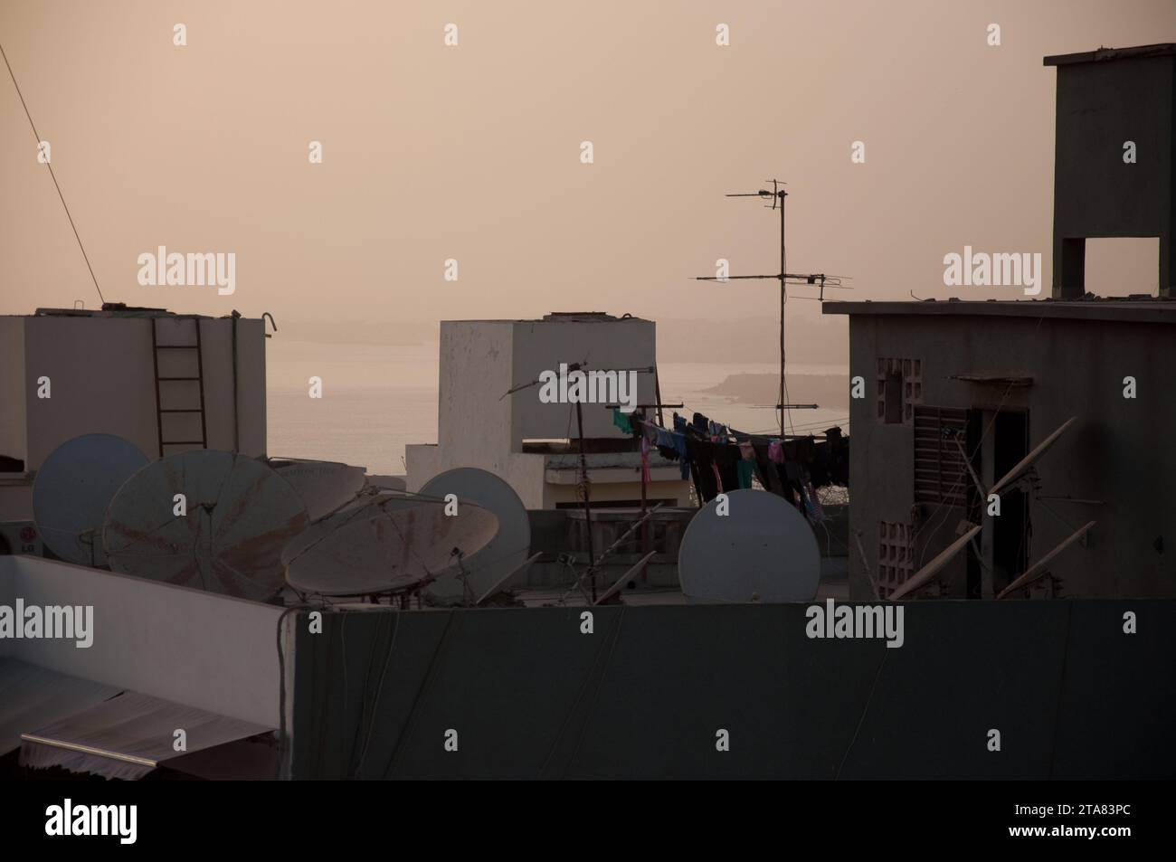 Rooftops at Dusk, Dakar, Senegal.  Atlantic Ocean in the distance.  Satellite dishes Stock Photo