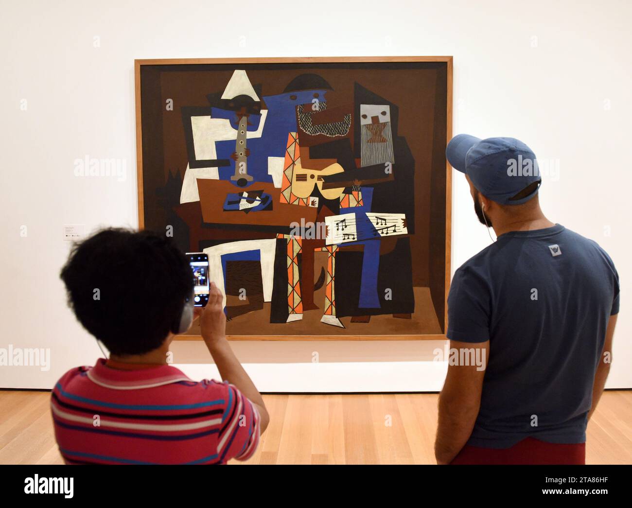 New York, USA - May 25, 2018: A visitors near the Pablo Picasso Three Musicians painting in Museum of Modern Art in New York City. Stock Photo