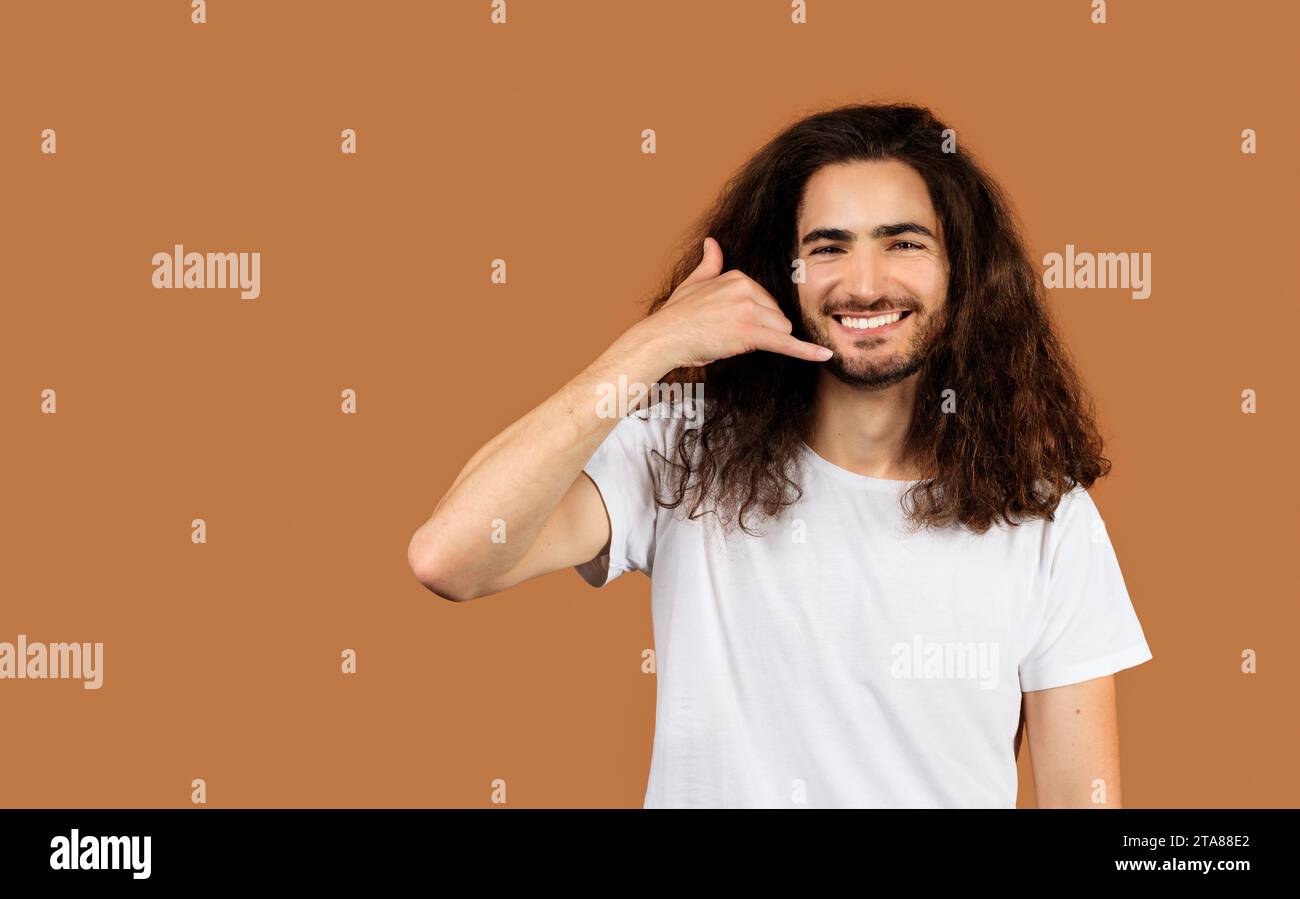 Cheerful Arabic young man gesturing Call Me against beige backdrop Stock Photo