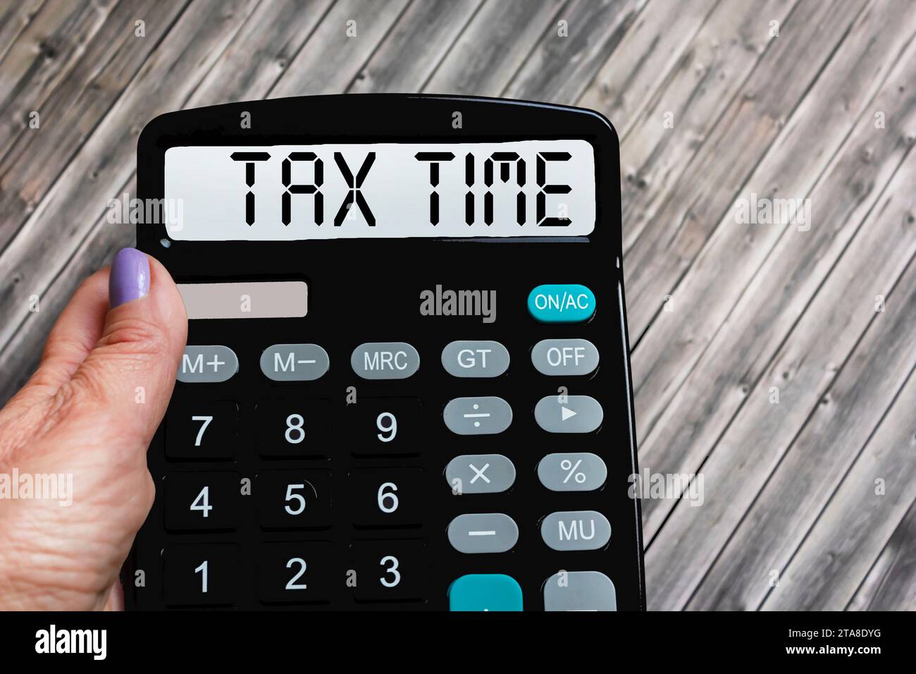 A woman's hand holds the word Tax time on a calculator. Business and taxation concept. Stock Photo