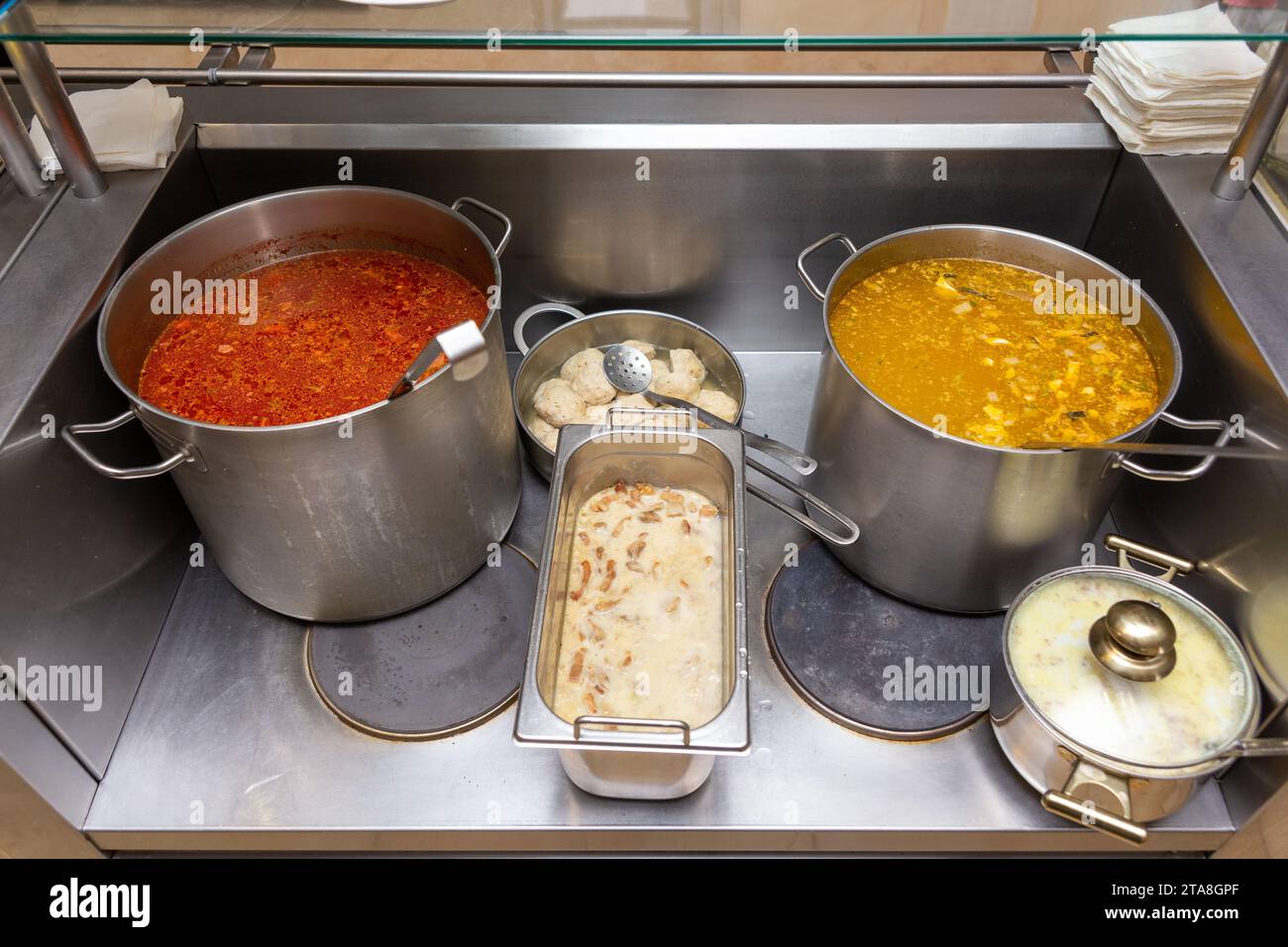 Soup heated pots with ladle in cafe. A variety of soups in metal pots