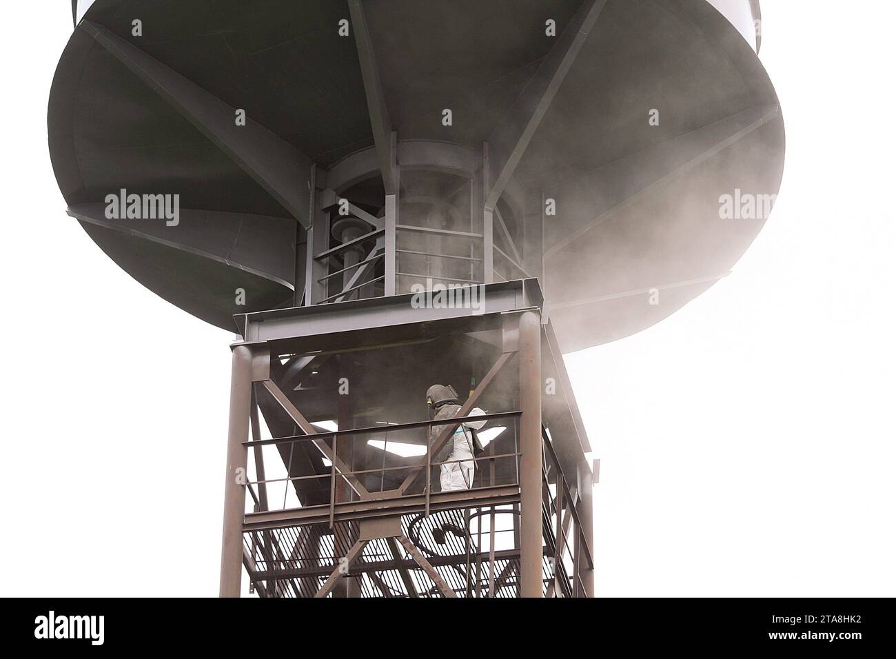 Sand blasting process. Industrial worker in protective uniform cleaning