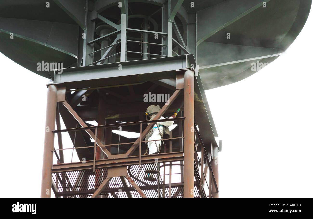 Sand blasting process. Industrial worker in protective uniform cleaning