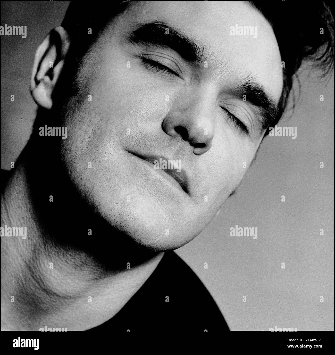 Black & white head & shoulders portrait of legendary rockstar, singer/songwriter Morrissey to promote his single “Sunny” in 1995 for Parlophone Records. It is a variation of the iconic “eyes closed” image used by Morrissey on his Penguin Classics book cover “Autobiography”. Stock Photo