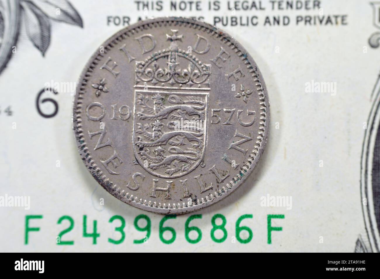 Reverse side of 1 one shilling Elizabeth II 1957 features Crowned English shield of arms dividing date, legend above, denomination below, on one Ameri Stock Photo