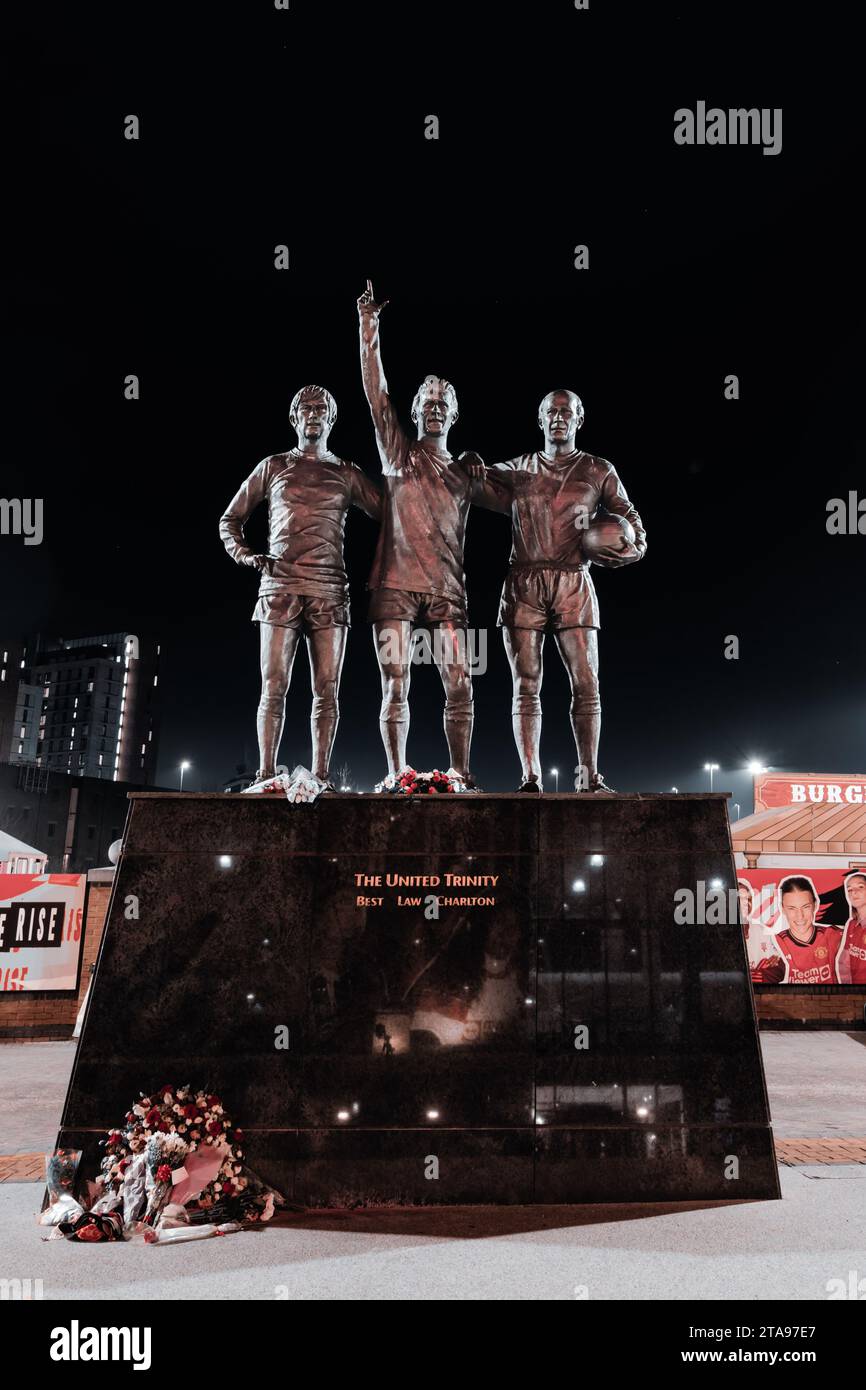 Trinity Statue of George Best, Bobby Charlton, and Denis Law outside of Manchester United FC at night, Old Trafford, Manchester, UK Stock Photo