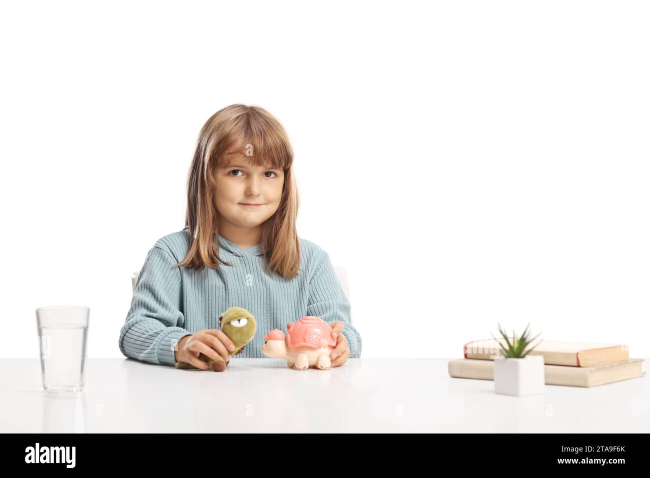 Cute little girl sitting at a table and playing with animal toys Stock Photo