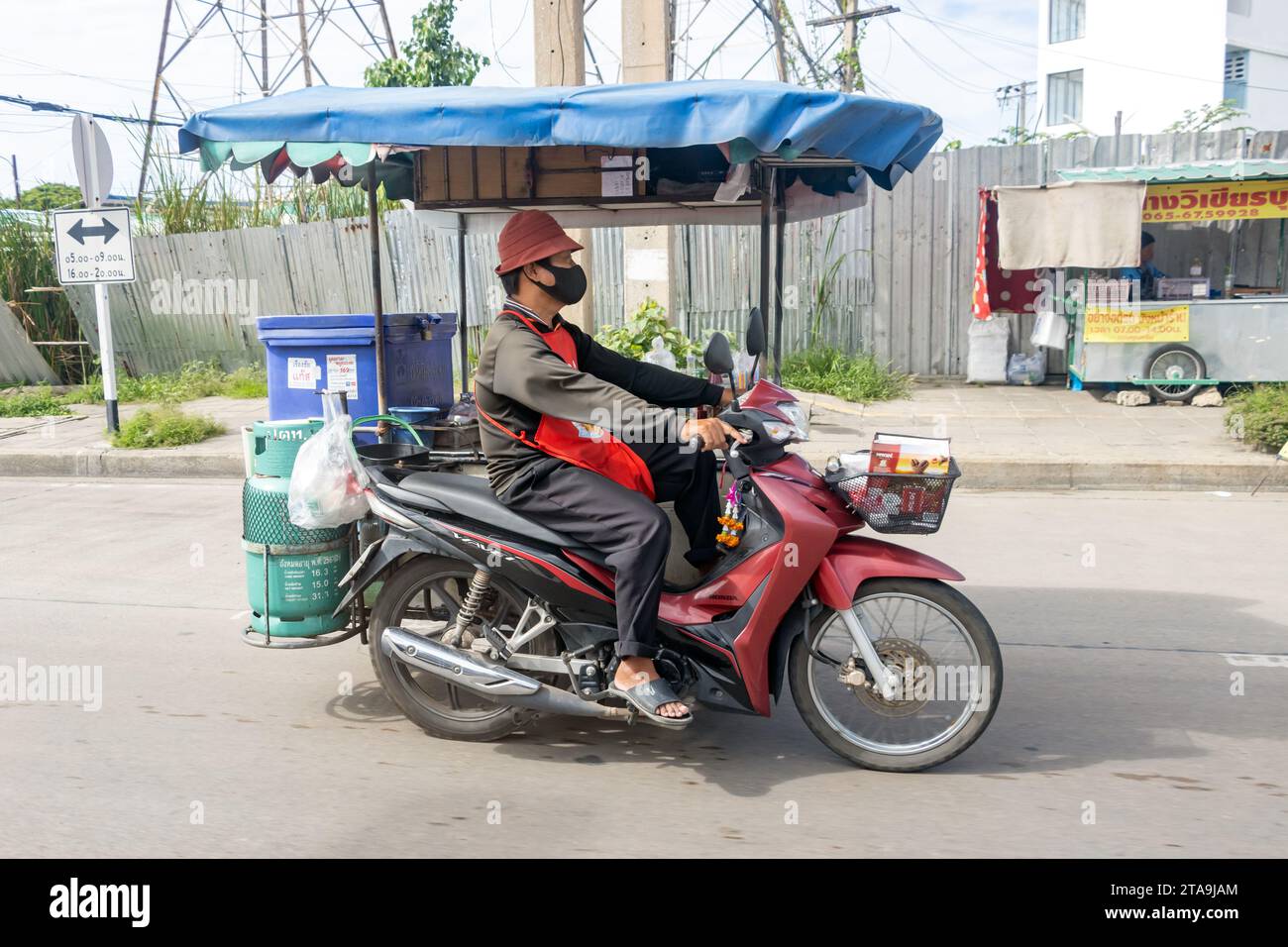 SAMUT PRAKAN, THAILAND, SEP 30 2023, The drinks vendor drives a motorbike with a mobile stand Stock Photo