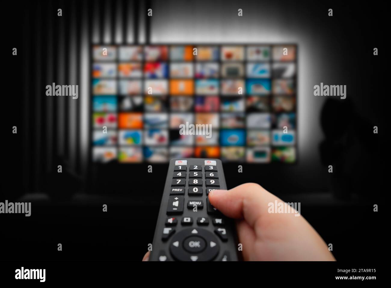 VOD service screen. Man watching TV with remote control in hand. Stock Photo
