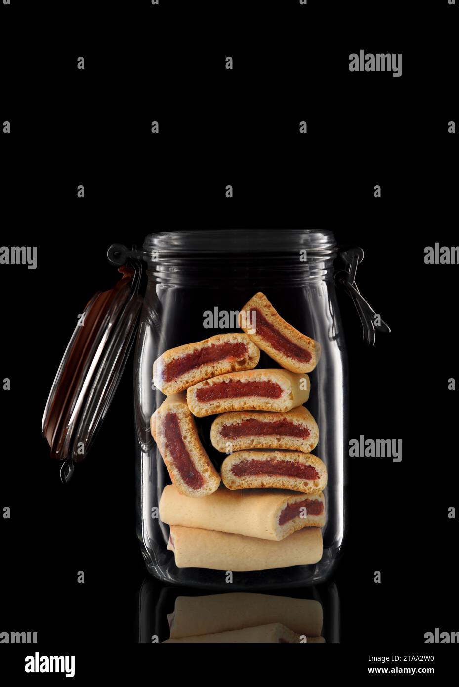 Fruit Newton cookies in a glass storage or canning jar isolated on black with reflection, with lid open. Stock Photo