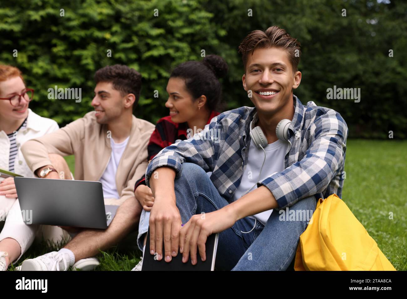 Group of happy young students learning together on green grass in park Stock Photo