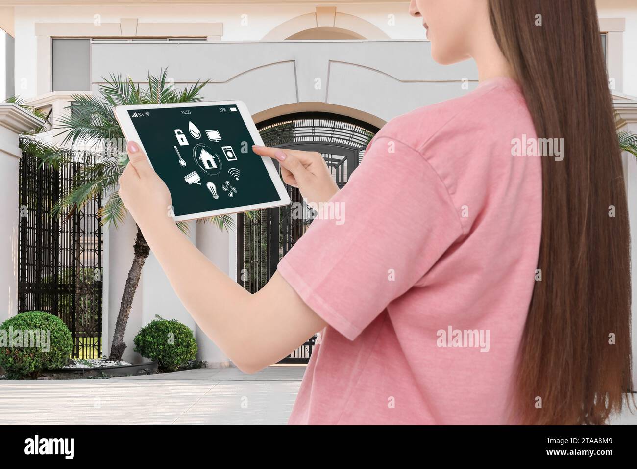 Woman using smart home control system via tablet near house outdoors ...