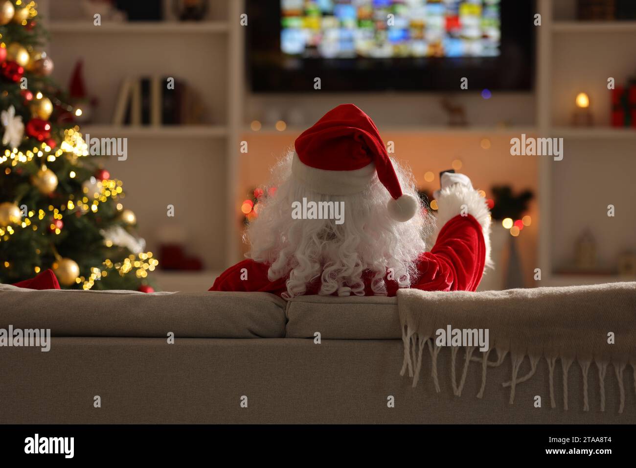 Santa Remote Control Merry Christmas. Santa Claus with remote control watching TV on sofa at ...