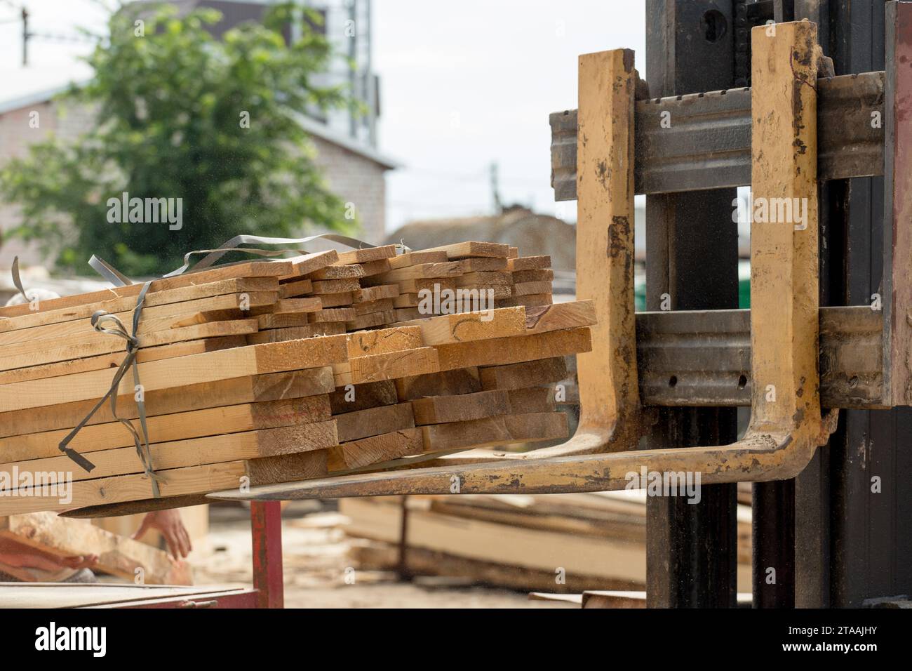 A forklift loads wooden planks, close-up. Wood industry. Stock Photo