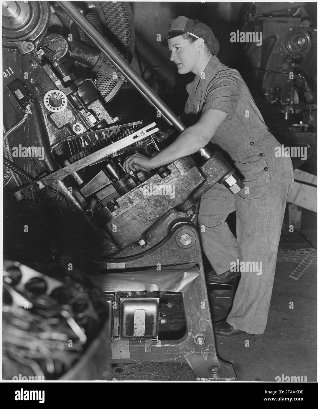 Virginia Ludwig goes to work on a punch press, stamping out discs from steel strips. Her well-fitting uniform is... Stock Photo