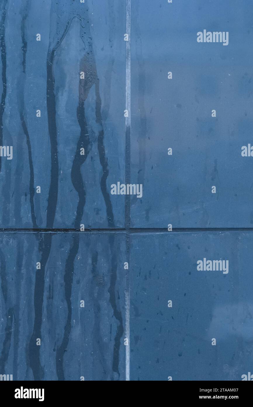 Blue streaks of paint spilled on the surface of ceramic tiles wall dirty texture background. Stock Photo