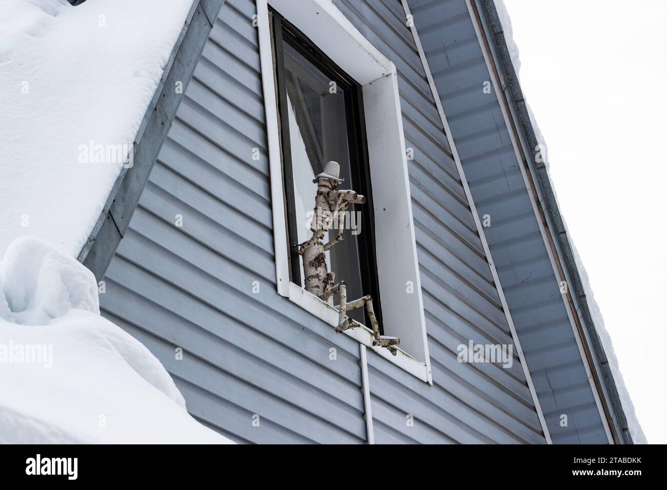 A wooden doll sitting on the window watches the territory Stock Photo