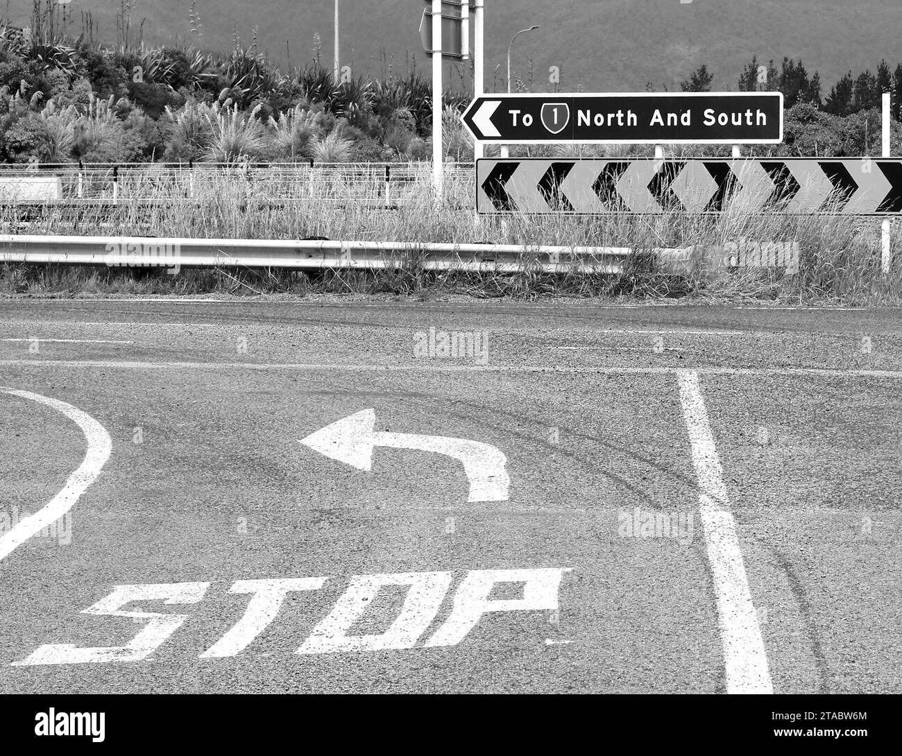 Country road and stop sign at major road. Signage shows the way to the north-south expressway  SH1. Drivers go left to head north and south. Stock Photo