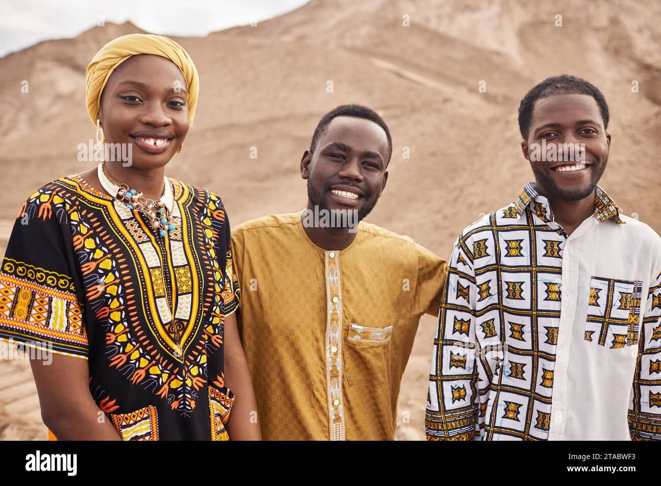 Group of young African American people wearing traditional clothing in desert, all smiling Stock Photo