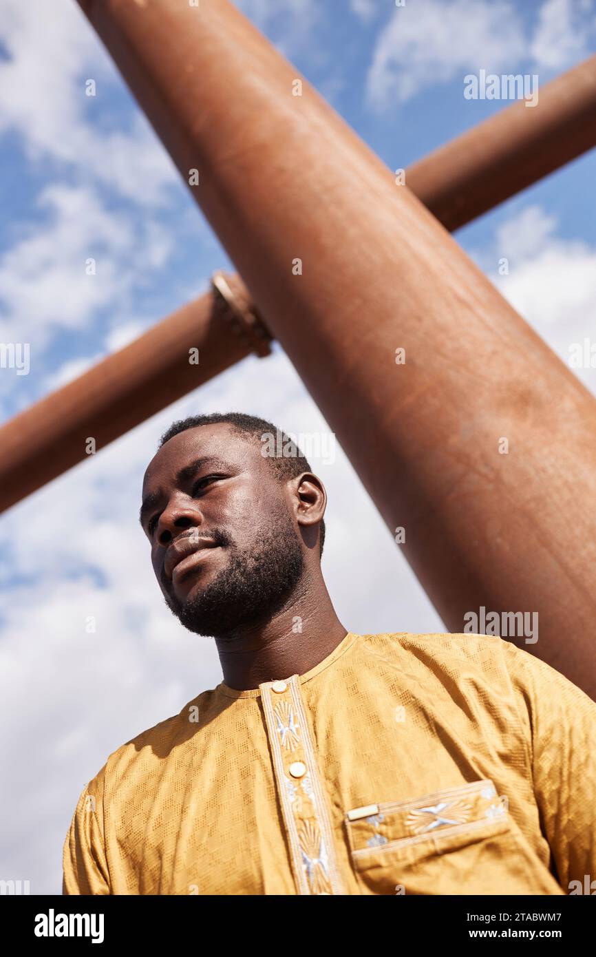 At angle shot of African American man looking away against sky with geometric shape Stock Photo
