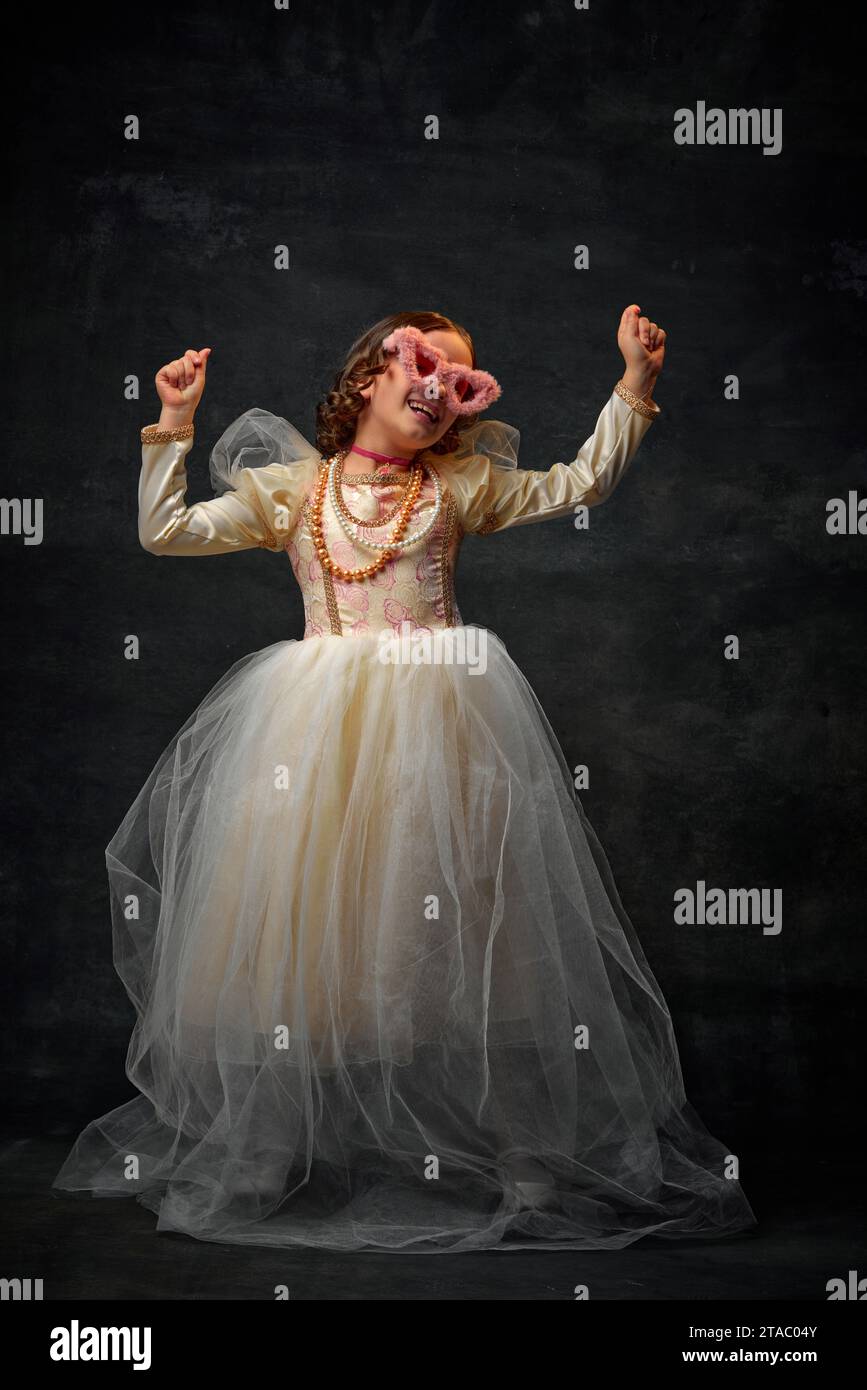 One little royal person, small girl dressed in old-fashioned costume with  modern accessories an dancing against vintage background Stock Photo - Alamy