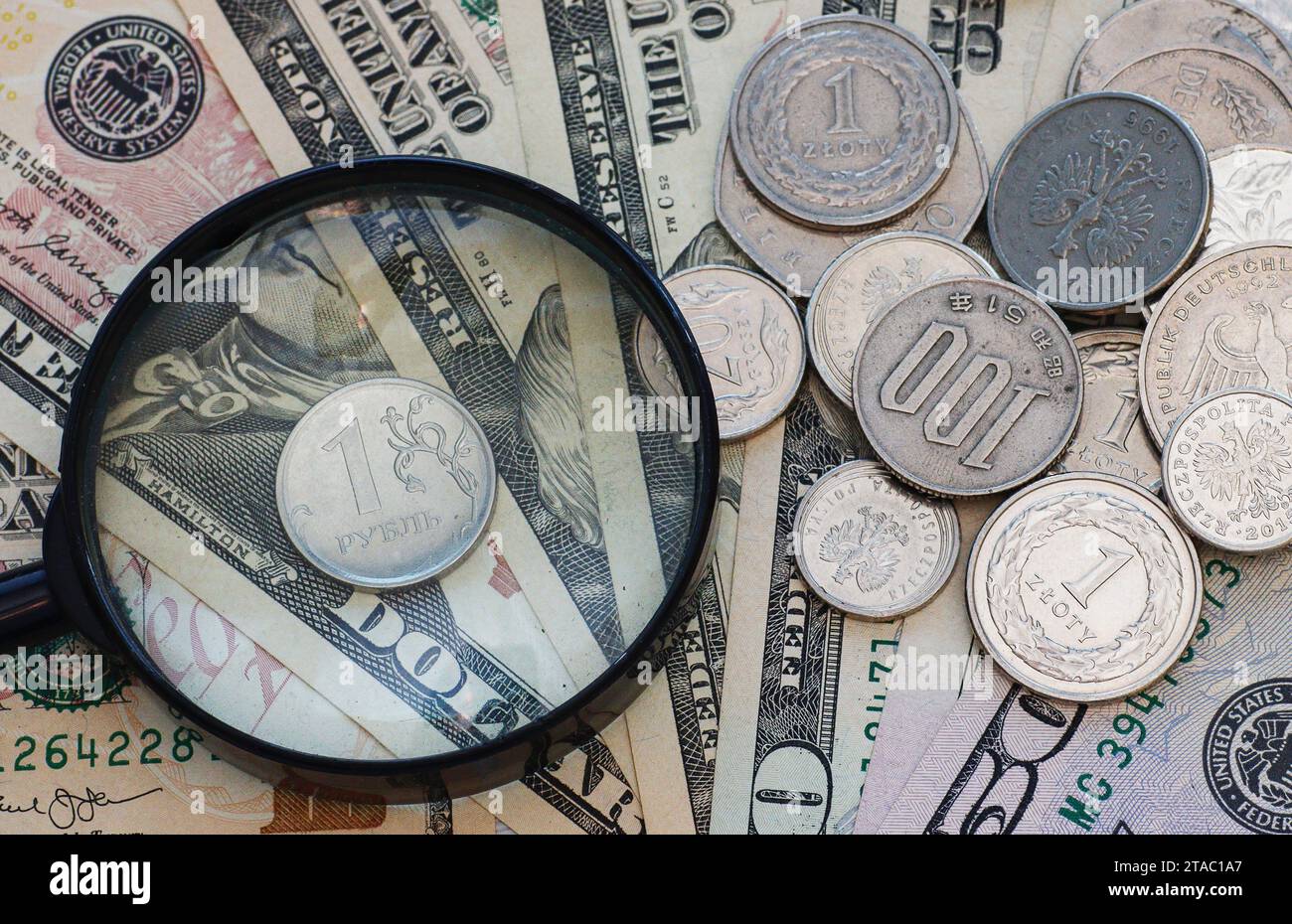 Ruble coin with a magnifying glass on a background of dollars and